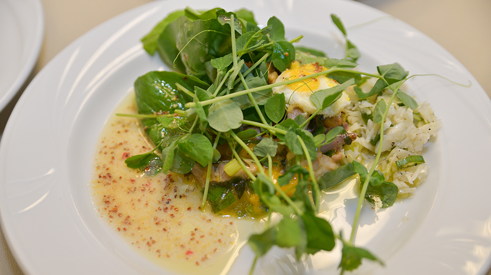 A dish of food with microgreens and a sauce