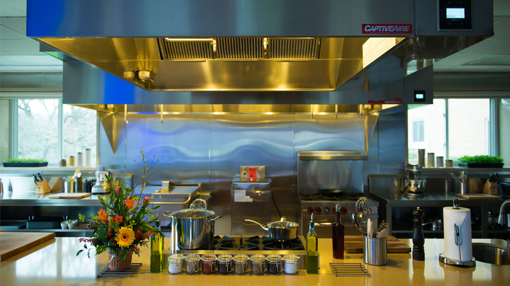 A stainless steel commercial kitchen with multiple ranges and cooking utensils